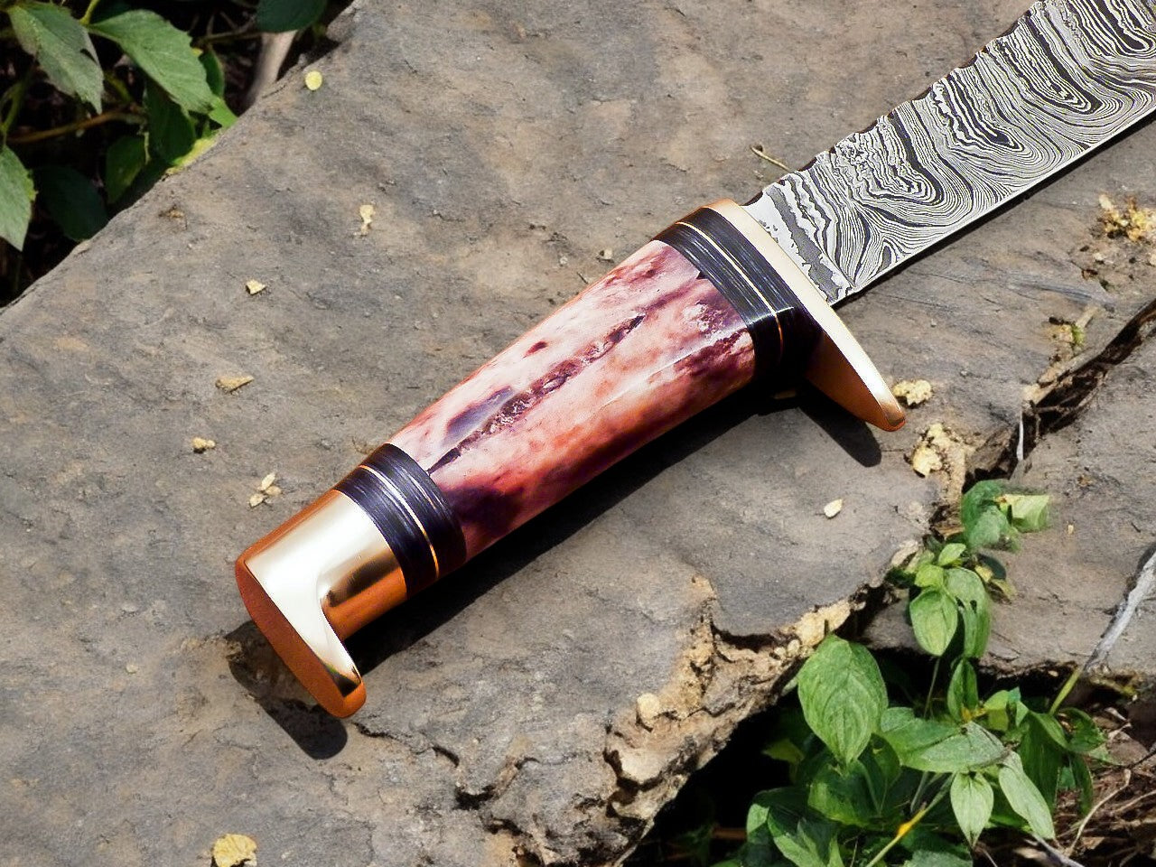 Damascus steel deer hunting knife with a focus on the blade's sharp edge.