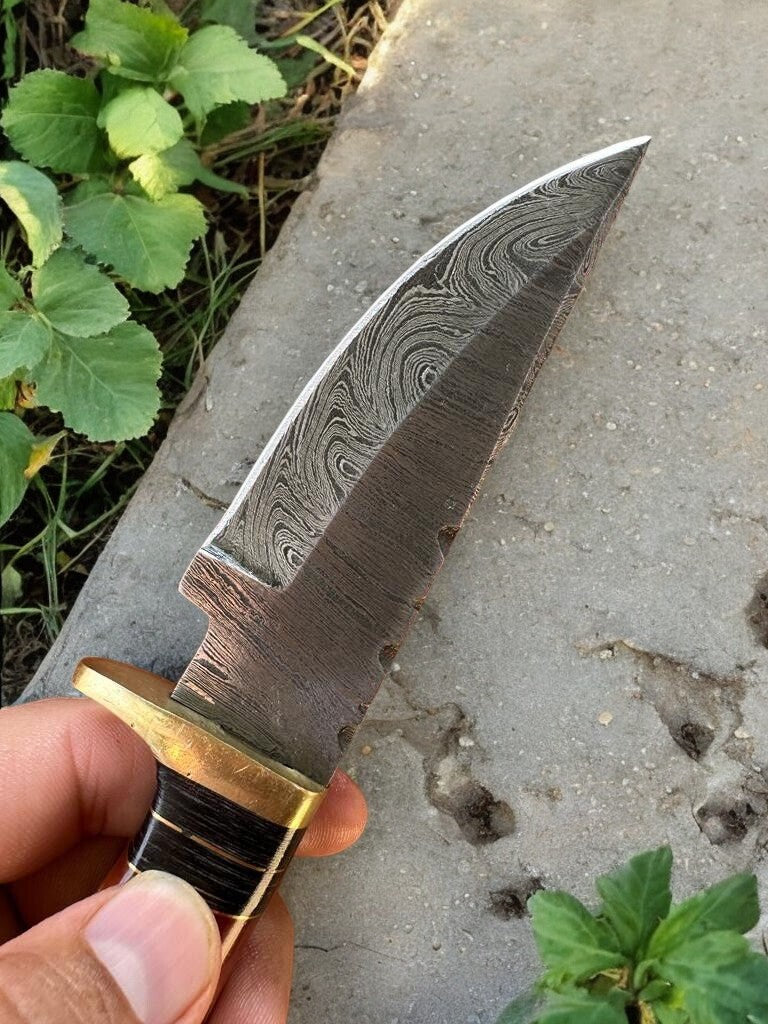 Close-up of the Damascus steel blade on the handmade hunting knife, highlighting the unique pattern.