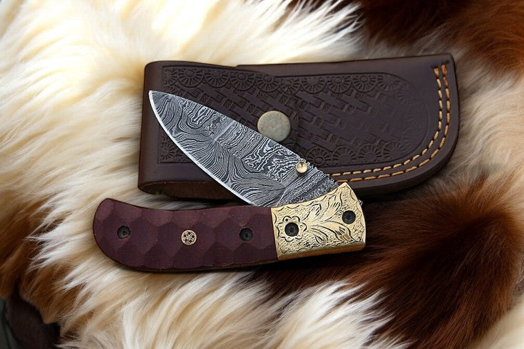 Pocket knife with Damascus steel blade and micarta handle displayed on leather case