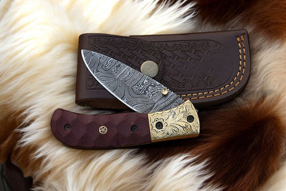 Pocket knife with Damascus steel blade and micarta handle displayed on leather case