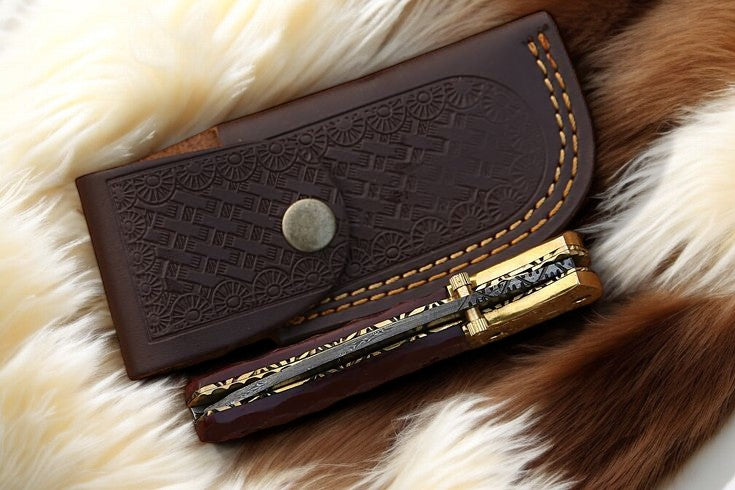 3.25-inch Damascus steel pocket knife next to leather case