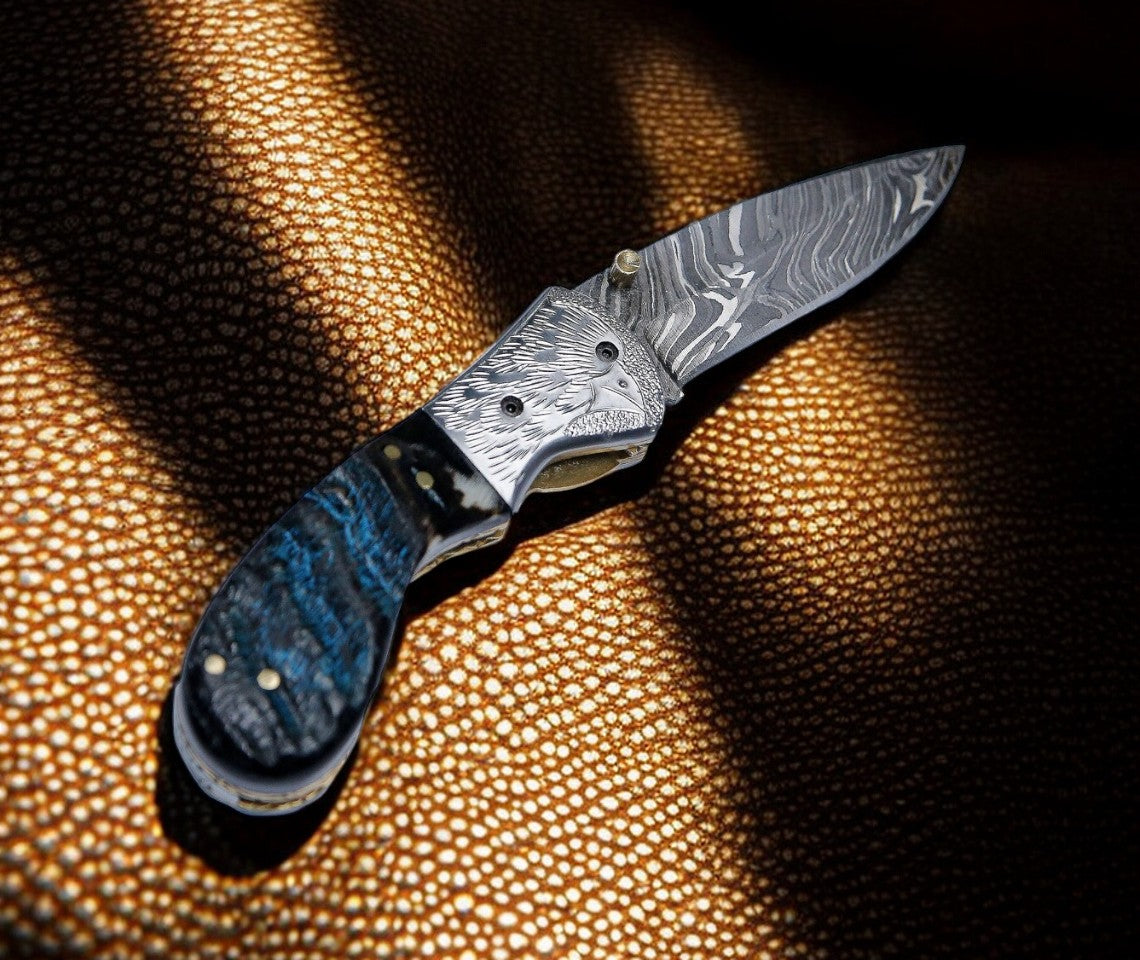 Damascus pocket knife with sheep horn handle and engraved steel bolster