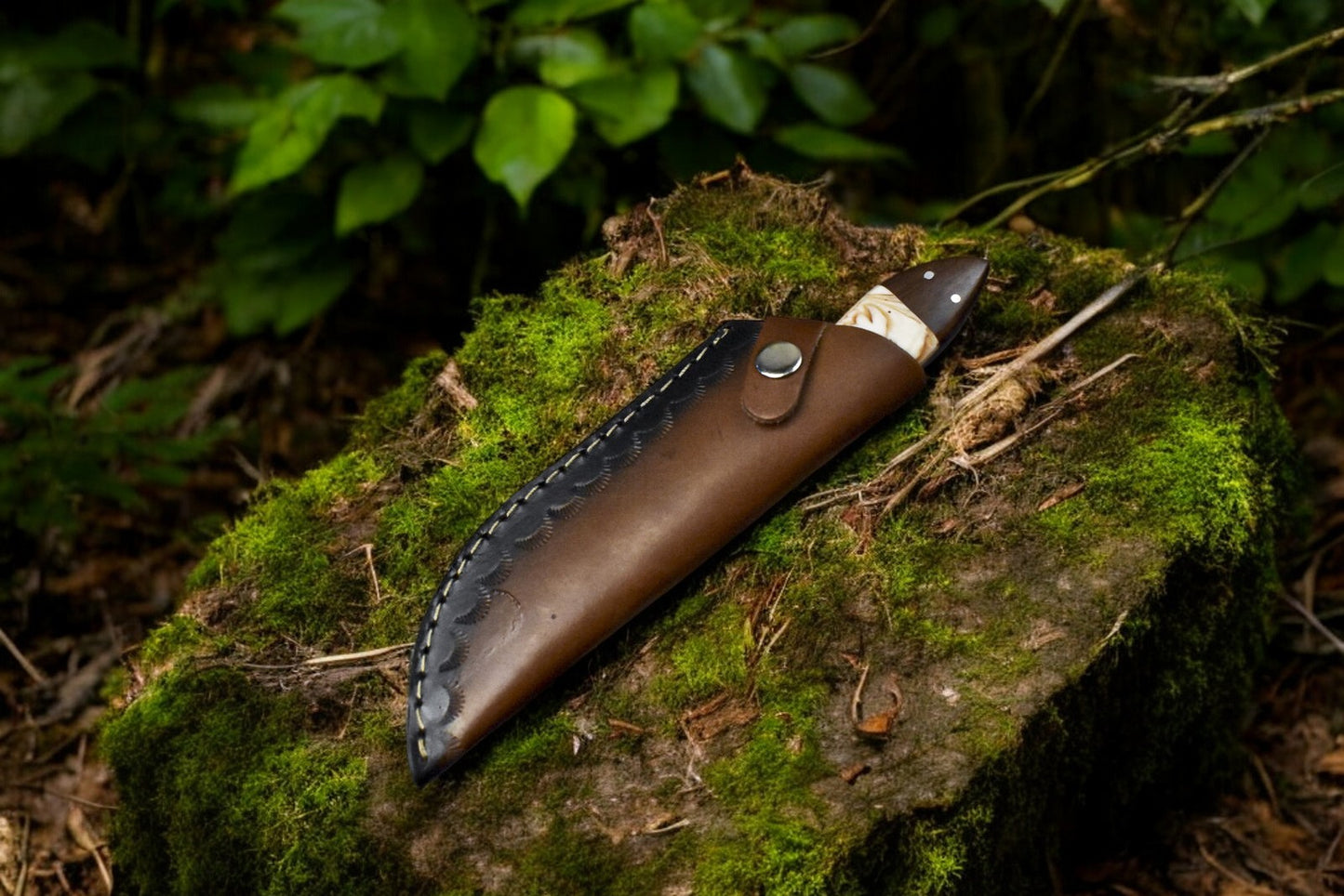 Damascus skinning knife resting inside its leather sheath.