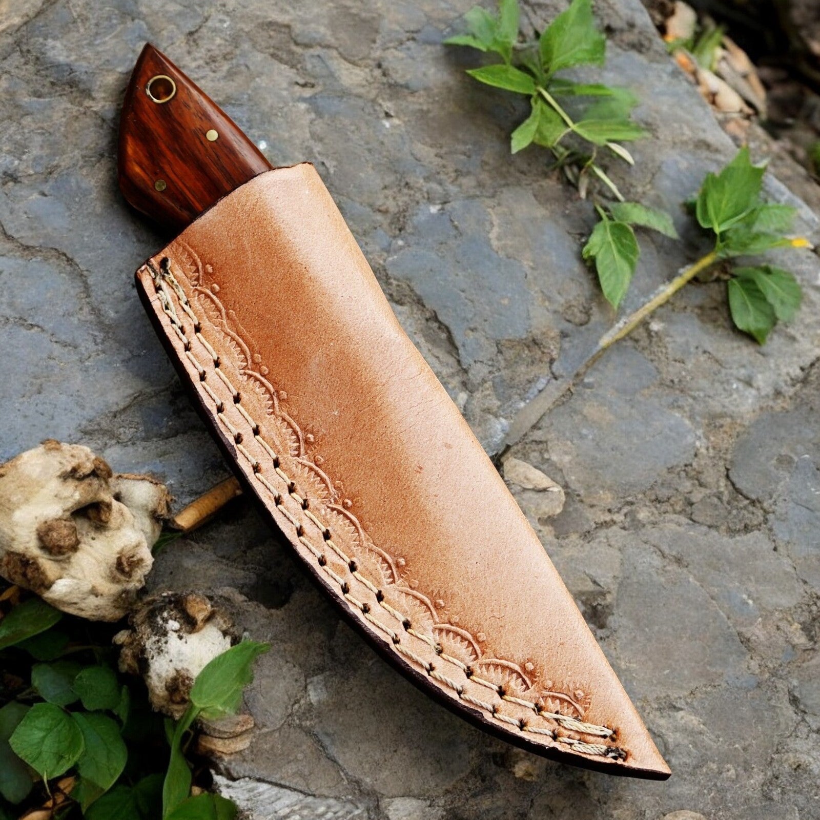 Leather sheath included with the Damascus steel hunting knife, displayed alongside the knife.
